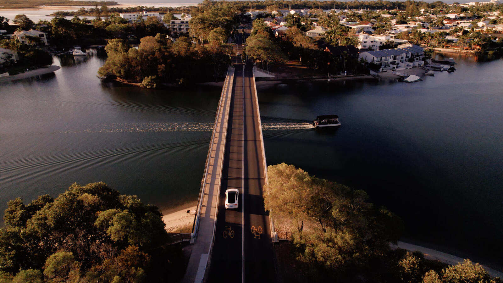 Electric airport transfer crossing the Noosa River bridge at sunset